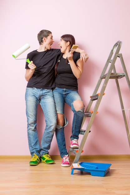 Photo of woman and man with brush standing on stepladder
