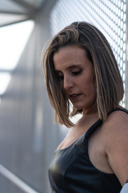 Photo of a woman scrolling through her phone while leaning on a fence