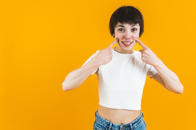 Photo of a woman smiling playfully and sticking her tongue a little with her fingers put to her