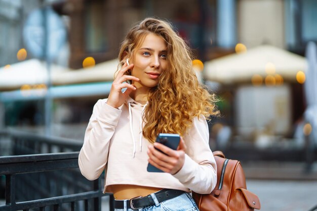 スマートフォンを使っている女性の写真街でメッセージを送っている女性街で時間を過ごしている美しい女性