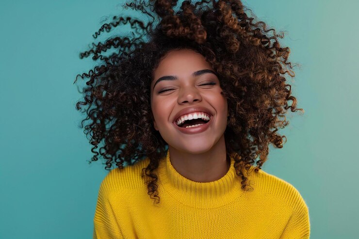 Photo photo of a woman with curly hair laughing and wearing yellow sweater isolated on solid color backgro