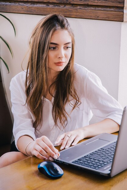 Фотография женщины с длинными каштановыми волосами, держащей серебряный персональный компьютер. женщина, работающая на ноутбуке.