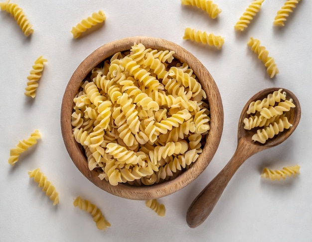 photo wooden bowl full of raw dry fusilli pasta