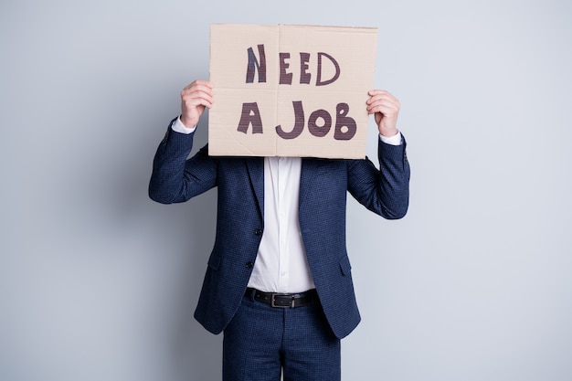 Photo of worker guy suffer financial crisis world crash bankrupt lost work hold carton placard banner search work place hide facial expression wear blue office suit isolated grey background