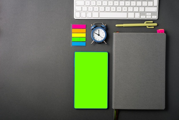 Photo of working desk with mock up, Green screen on tablet, agenda, laptop and stickers with alarm clock