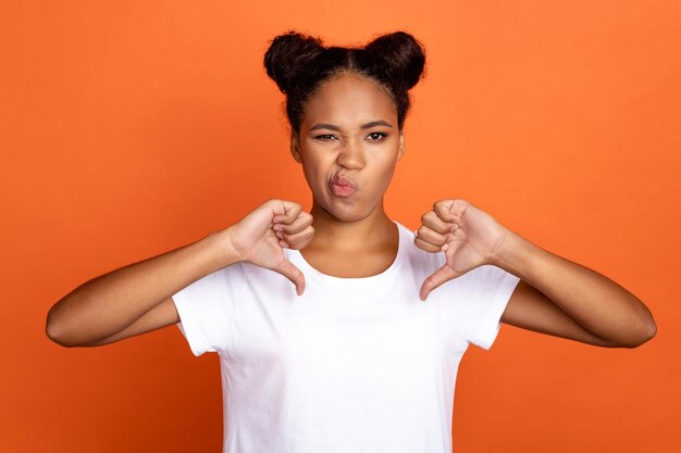 Photo of young african woman show thumbdown bad quality advertisise isolated over orange color background