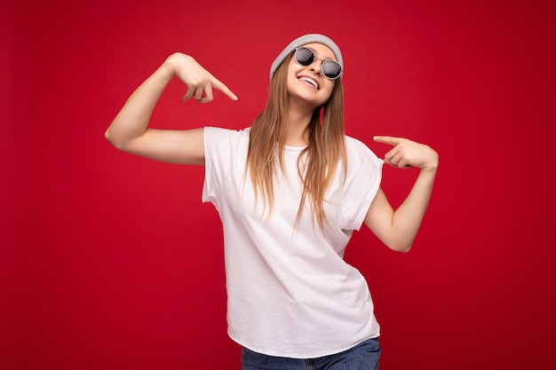 Foto di una giovane donna bionda scura attraente felice e positiva sorprendente con emozioni sincere che indossano