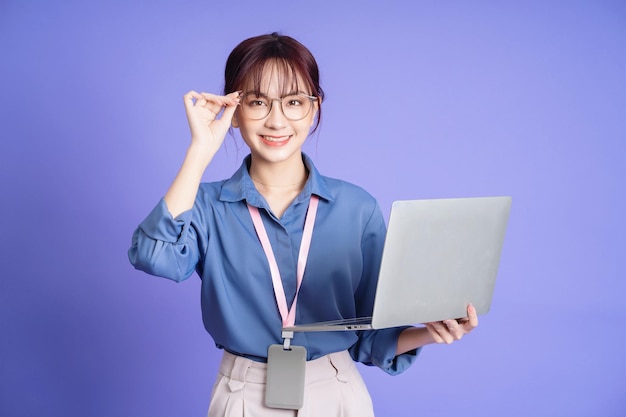 Photo of young Asian businesswoman holding laptop on background