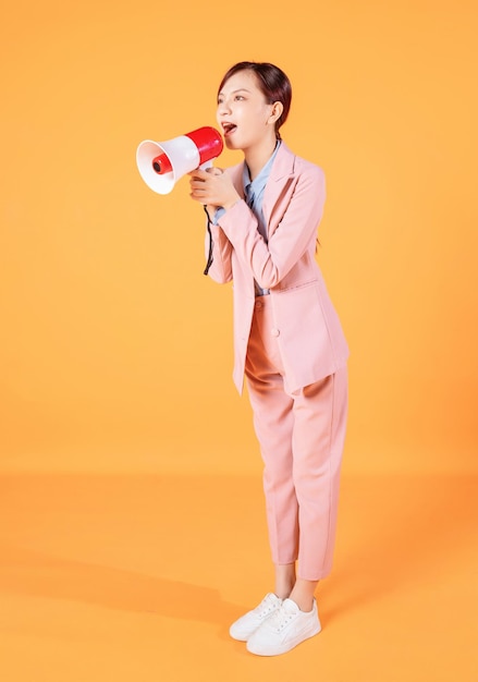 Photo of young Asian businesswoman holding megaphone on background