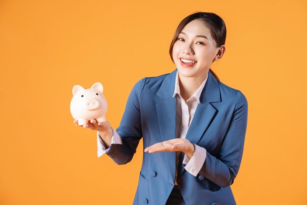 Photo of young asian businesswoman holding piggy bank on background