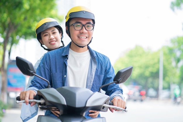 バイクを運転するアジアの若いカップルの写真