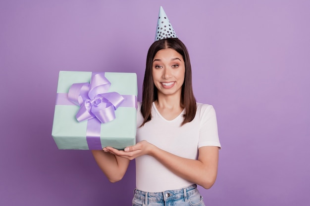 Photo of young attarctive girl wearing paper cap holding in hands giftbox celebration isolated over vivid violet color background