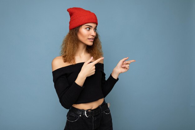 Photo of young attractive brunette curly woman with sincere emotions wearing black crop top and red