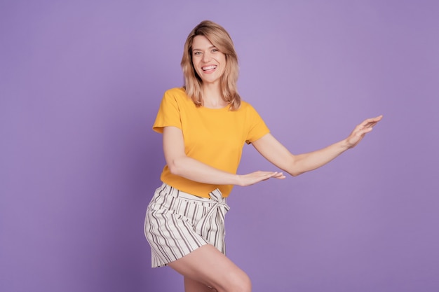 Фото молодой привлекательной женщины, счастливой позитивной улыбки, танцевальной дискотеки, изолированной на фиолетовом цветном фоне