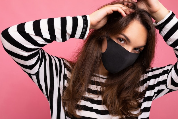 Photo of young attractive woman wearing handmade cotton fabric face mask isolated over colourful background wall. Protection against COVID-19.