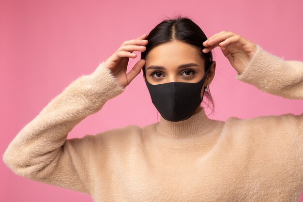 Photo of young attractive woman wearing handmade cotton fabric face mask isolated over colourful background wall. Protection against COVID-19.