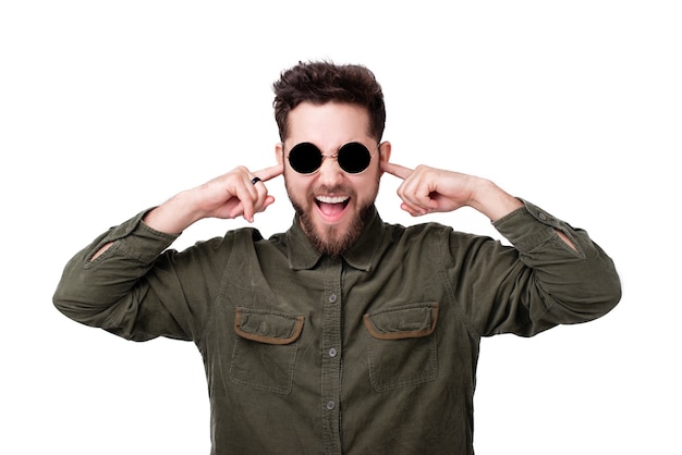 Photo of young bearded man wearing sunglasses, and putting fingers in ears for 
less noise