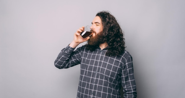 Foto foto di un giovane uomo barbuto con lunghi capelli ricci che beve la sua tazza di caffè mattutina