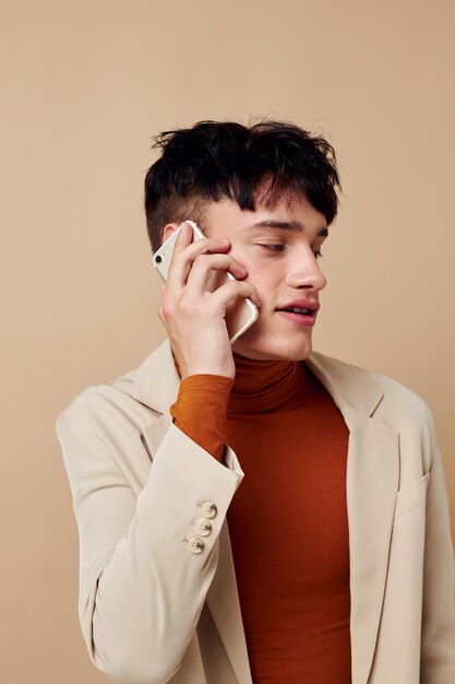 Photo young boyfriend in a beige jacket talking on the phone Lifestyle unaltered