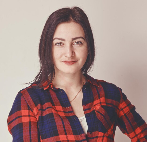 Photo of a young brunette woman dressed in checked long sleeve shirt