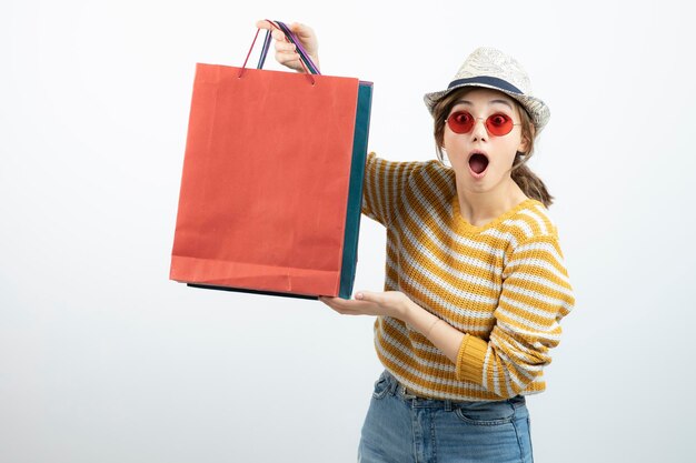 Photo of young brunette woman in sunglasses holding shopping bags. High quality photo