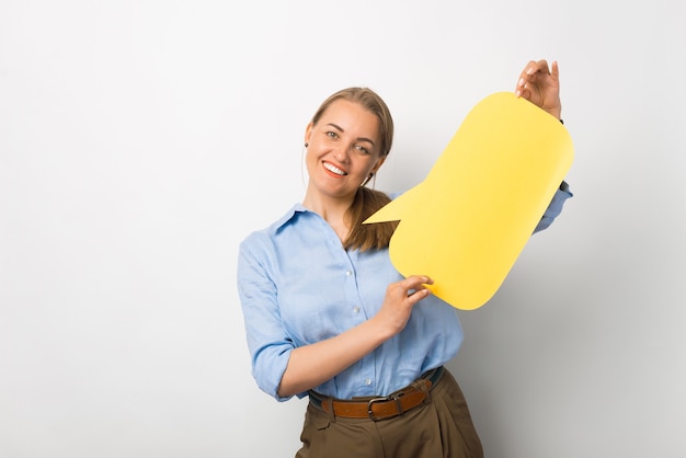 Photo of young business woman in casual holding empty yellow speech bubble with free space for text