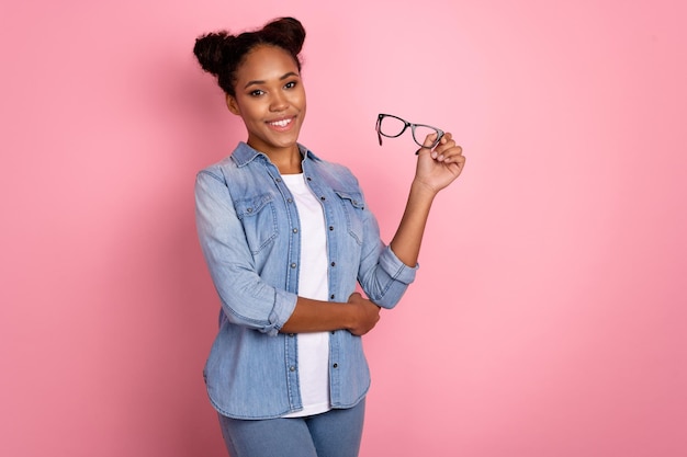 Photo of young cheerful african lady hold eyeglasses marleter expert isolated over pink color background