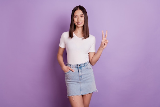 Photo of young cheerful girl happy positive smile show peace cool v-sign isolated over violet color background