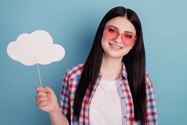 若い陽気な女の子の写真は、ターコイズ色の背景に分離された紙雲スティック天気アイウェアを保持します