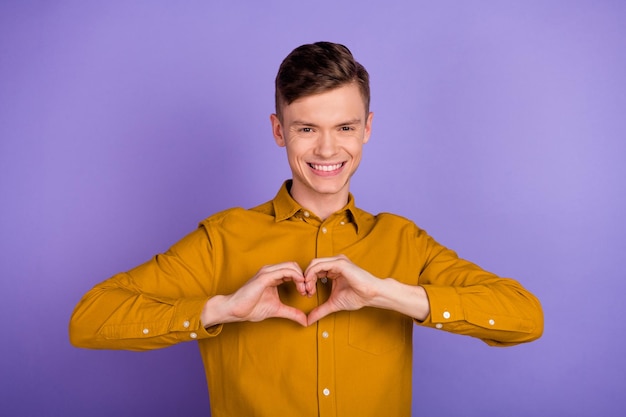 Photo of young cheerful guy show fingers heart symbol romantic date isolated over violet color background