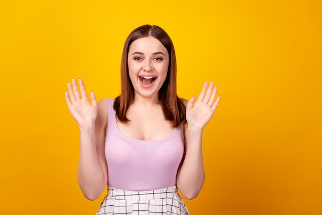 Photo of young cheerful lady excited waving hands hello symbol isolated over yellow color background