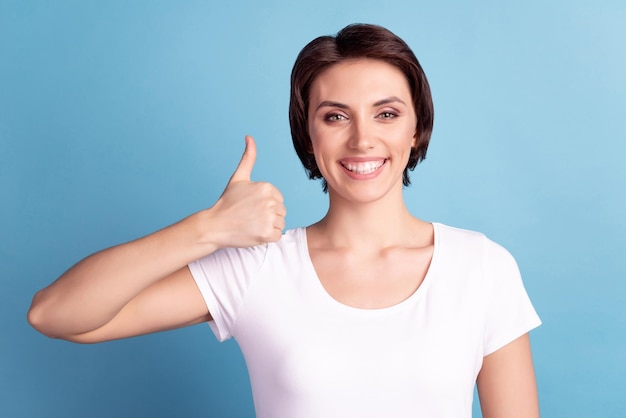 Photo of young cheerful lady promoter show thumb-up approve recommend ads isolated over blue color background.