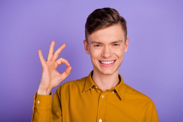 Photo of young cheerful man promoter show fingers okey symbol promo approve isolated over violet color background