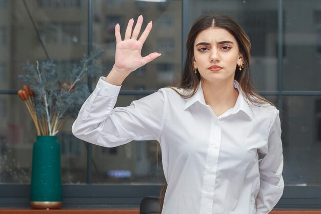 Photo of young confident girl raised her hand and looking at the camera