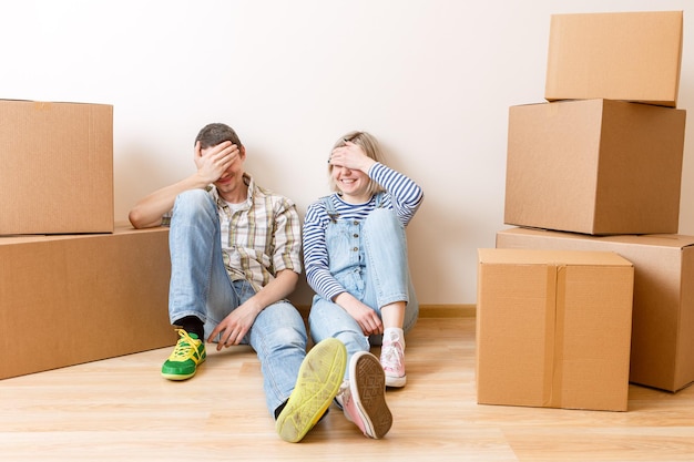 Photo of young couple among cardboard boxes