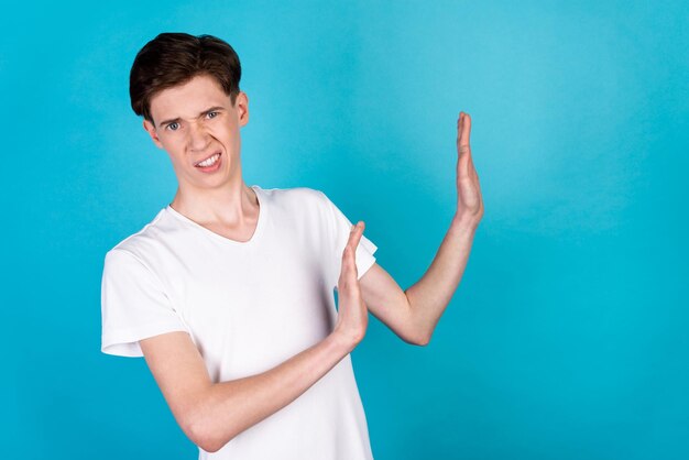 Photo of young displeased man show arms no stop enough refuse symbol isolated over blue color background