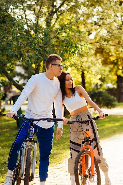 photo of a young embracing couple standing outside with their bicycles looking at something