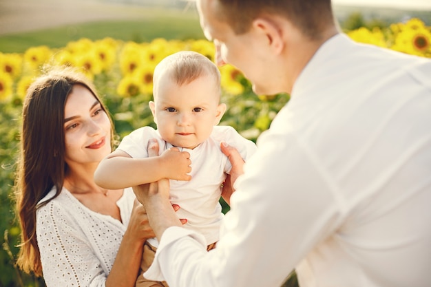 Photo of a young family at the sunflowers field on a sunny day. 