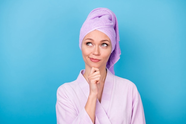 Photo of young girl finger chin interested look up empty space wear purple towel turban bath robe isolated blue color background