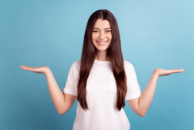 Photo of young girl hold palms recomend vs scales solution demonstrating proposition isolated over blue color background.