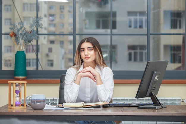 Photo of a young girl sitting at the desk and put her hands together High quality photo