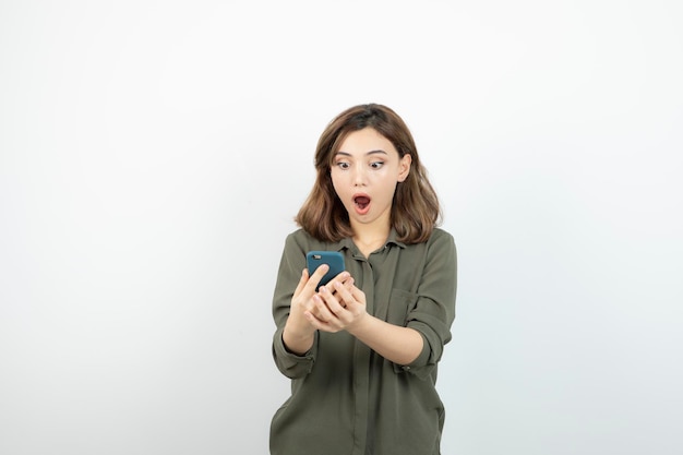 Photo of young girl with cellphone standing and checking her messages. High quality photo