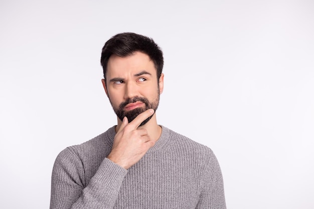 Photo of young guy arm touch chin wondered look empty space thoughtful isolated over grey color background