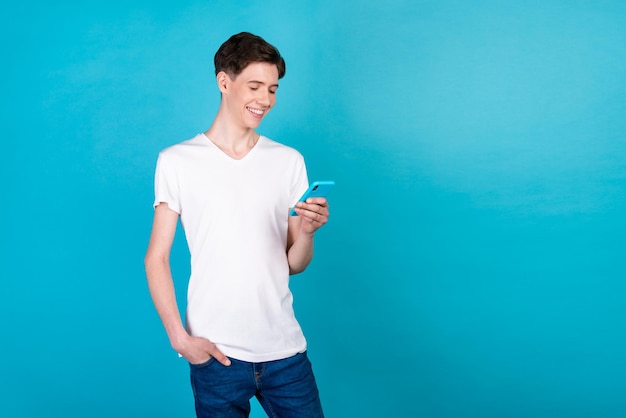 Photo of young guy chat type sms cellphone comment like post subscribe isolated over blue color background