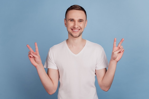 Foto di un giovane bell'uomo felice sorriso positivo che mostra un gesto di v-sign fresco isolato su sfondo di colore blu pastello