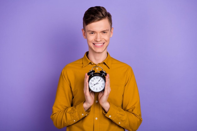 Photo of young handsome man hold hands clock alarm morning deadline chief isolated over violet color background