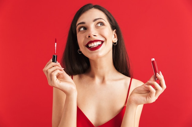 Photo photo of young happy excited woman posing isolated holding lip gloss doing makeup.