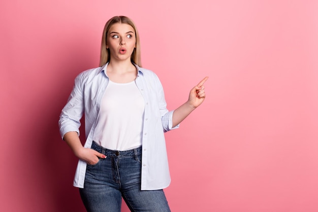 Photo of young impressed girl look indicate finger empty space\
discount advert isolated over pink color background