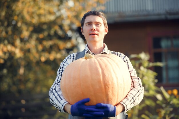 Photo of young man in blue gloves holding pumpkin