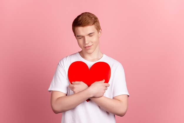 Foto di un giovane abbraccio abbraccia la carta presente cuore cupido sentimenti isolati su sfondo di colore rosa
